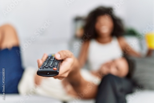 Man and woman couple watching tv and drinking coffee at home
