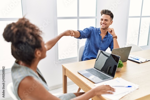 Man and woman business workers smiling confident bump fists at office