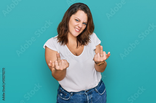 Young plus size woman wearing casual white t shirt showing middle finger doing fuck you bad expression, provocation and rude attitude. screaming excited photo