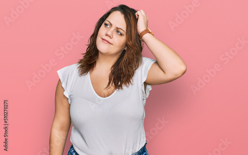 Young plus size woman wearing casual white t shirt confuse and wondering about question. uncertain with doubt, thinking with hand on head. pensive concept.