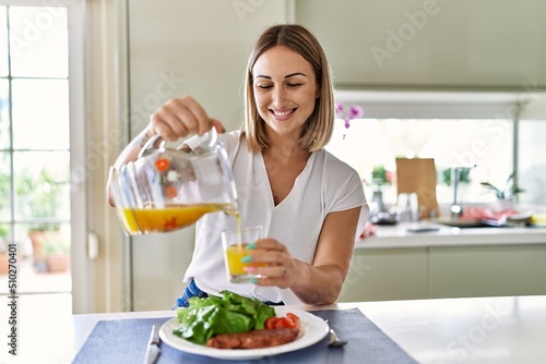 Young caucasian girl smiling happy having lunch at the kitchen.