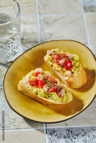 Crostini or bruschetta with softened avocado, ham and tomatoes. Toast with mashed avocado © Irina Burakova
