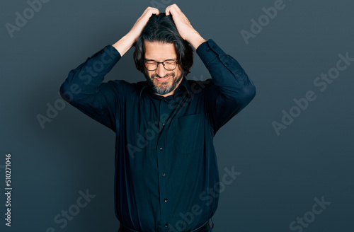 Middle age caucasian man wearing casual clothes and glasses suffering from headache desperate and stressed because pain and migraine. hands on head.