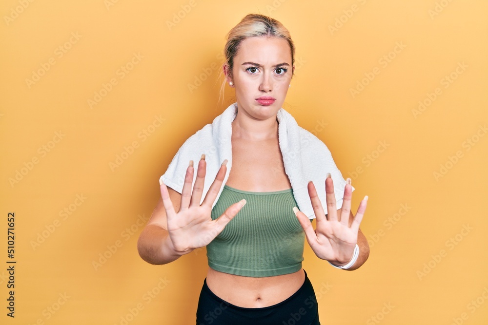 Young blonde girl wearing sportswear and towel moving away hands palms showing refusal and denial with afraid and disgusting expression. stop and forbidden. Young blonde girl wearing sportswear and towel moving away hands palms showing refusal and denial with afraid and disgusting expression. stop and forbidden.
