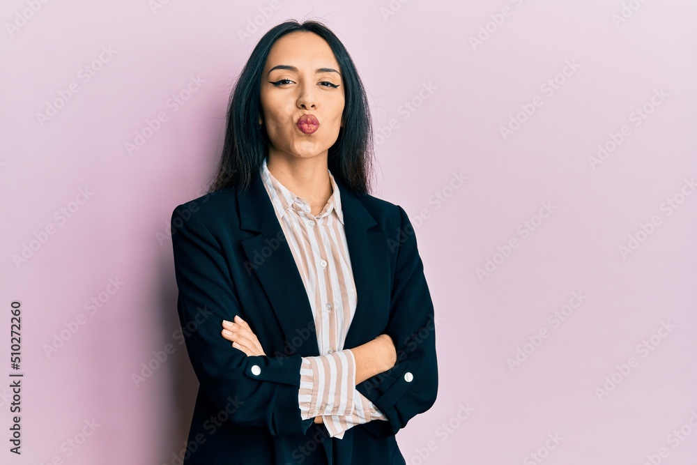 Young hispanic girl wearing business clothes with arms crossed looking at the camera blowing a kiss being lovely and sexy. love expression. Young hispanic girl wearing business clothes with arms crossed looking at the camera blowing a kiss being lovely and sexy. love expression.