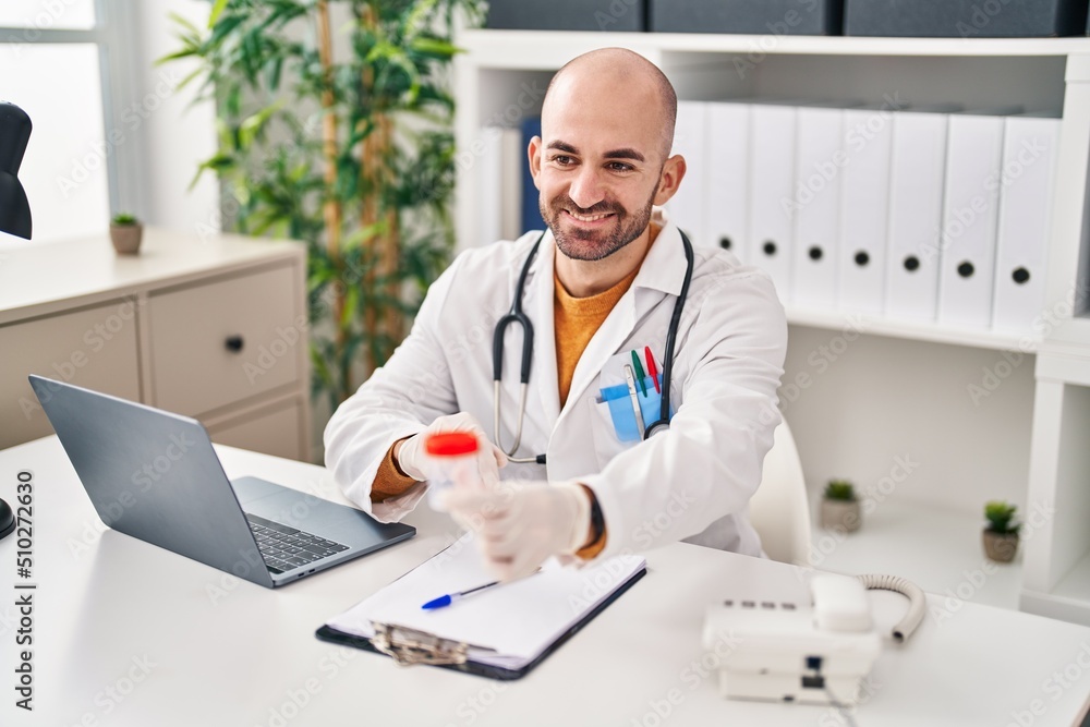 Young man wearing doctor uniform holding analysis test tube at clinic Young man wearing doctor uniform holding analysis test tube at clinic