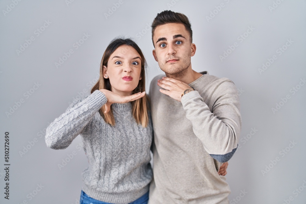 Young hispanic couple standing over white background cutting throat with hand as knife, threaten aggression with furious violence Young hispanic couple standing over white background cutting throat with hand as knife, threaten aggression with furious violence