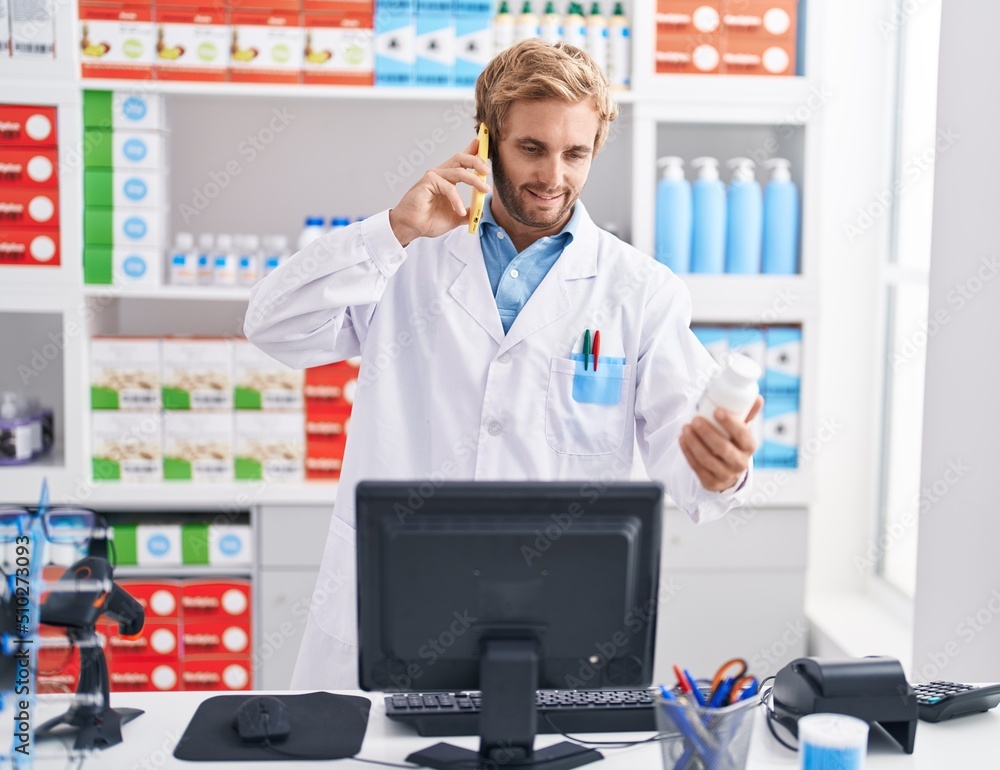 Young man pharmacist talking on the smartphone holding pills at pharmacy