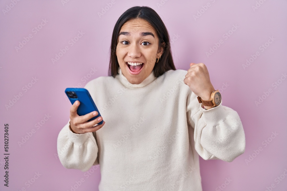 Young south asian woman using smartphone screaming proud, celebrating victory and success very excited with raised arms Young south asian woman using smartphone screaming proud, celebrating victory and success very excited with raised arms