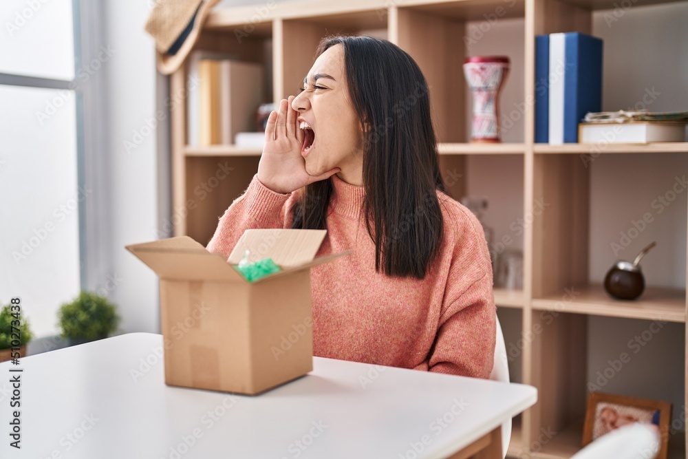 Young south asian woman opening cardboard box clueless and confused with open arms, no idea and doubtful face. Young south asian woman opening cardboard box clueless and confused with open arms, no idea and doubtful face.