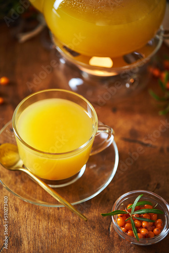 Glass teapot and sea buckthorn tea cup on wooden background