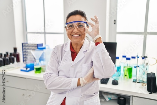 Fototapeta Naklejka Na Ścianę i Meble -  Middle age hispanic woman wearing scientist uniform working at laboratory