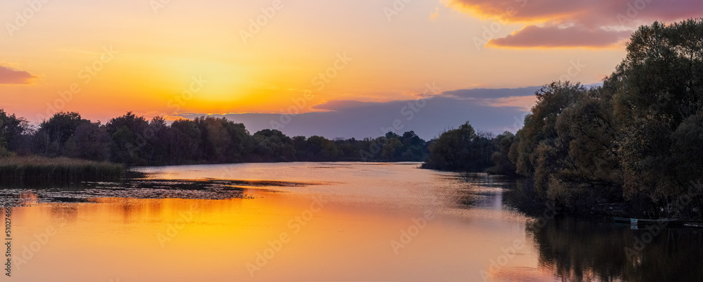 Sunrise or sunset on the river. Reflection of the sky and clouds in the river water