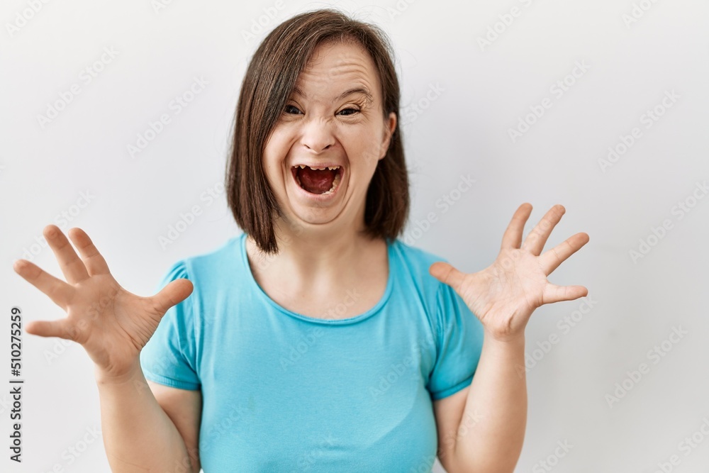Young down syndrome woman standing over isolated background celebrating mad and crazy for success with arms raised and closed eyes screaming excited. winner concept Young down syndrome woman standing over isolated background celebrating mad and crazy for success with arms raised and closed eyes screaming excited. winner concept