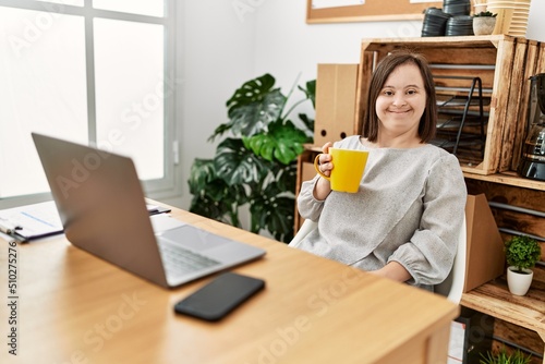 Brunette woman with down syndrome drinking a cup of coffee at business office