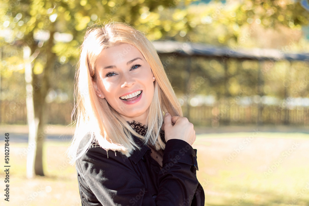 pretty blonde woman smiling happily in a park dressed in black pretty blonde woman smiling happily in a park dressed in black