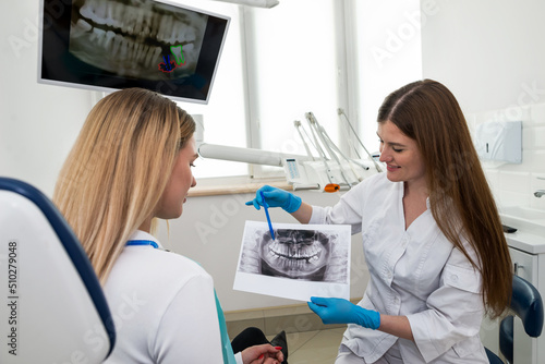 The dentist shows the x-ray image to the patient. People  medicine  dentistry  technology and healthcare concept.
