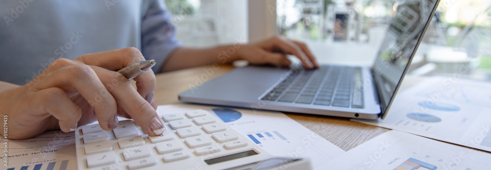 Financial or accounting professionals use a laptop to analyze the company's revenue-expenses graph to prepare for presentation to the chief executive and partner, businesswomen working in the room. Financial or accounting professionals use a laptop to analyze the company's revenue-expenses graph to prepare for presentation to the chief executive and partner, businesswomen working in the room.