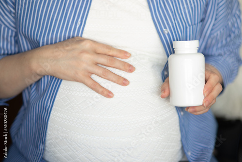 vitamins for expectant mothers, a pregnant woman holds a jar of pills in her hands, health and medicine in pregnancy
