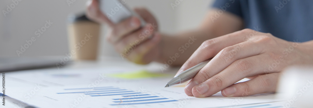 Asian male employees are analyzing market data via smartphones and have Calculator to calculate the company's finances In a private office at home, Working at home and new normal concept. Asian male employees are analyzing market data via smartphones and have Calculator to calculate the company's finances In a private office at home, Working at home and new normal concept.