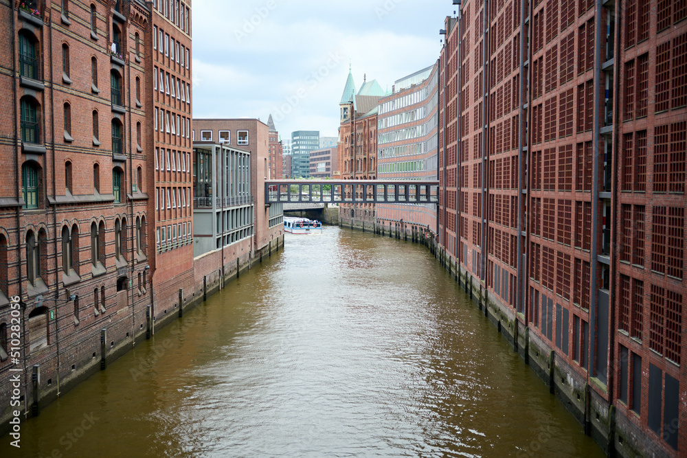  View of famous Speicherstadt warehouse district. Old brick building, river canal of Hafencity quarter. Hamburg skyline.
