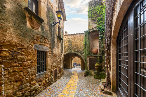 Fototapeta Naklejka Na Ścianę i Meble -  The wet streets of the medieval village of Pals, Spain after a summer rainstorm along the Costa Brava coast of the Catalonian region.