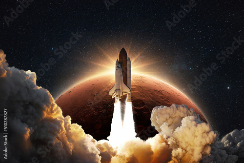Fototapeta Naklejka Na Ścianę i Meble -  Shuttle rocket successfully takes off into space on a background of the red planet Mars with the sunrise. Spaceship with clouds of smoke and blast liftoff into stellar sky. Concept of space travel