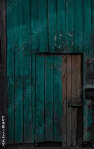 Old dark wooden rustic look barn doors. Metal hinges, and lock holders placed on the rough texture doors are very rusty.