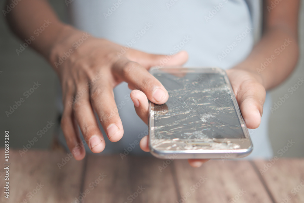 Close up of man hand holding broken smart phone.