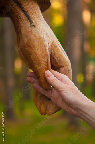 Wooden hand and women hand in handshake to show friendship and respect on nature background. With copyspace.