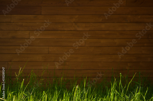 Wooden wall  background framed with green bushes and grass