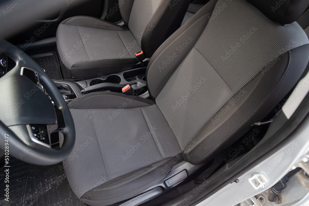 Comfortable front seats inside the car: the driver and passenger, tied with genuine black leather, modern interior design, the steering wheel covered with black wood and a luxurious center console