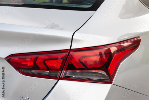 Close-up of a red LED rear brake light replaced after an accident on a white car in the back of a sedan after washing and cleaning for pre-sale preparation. Taillights with brake light