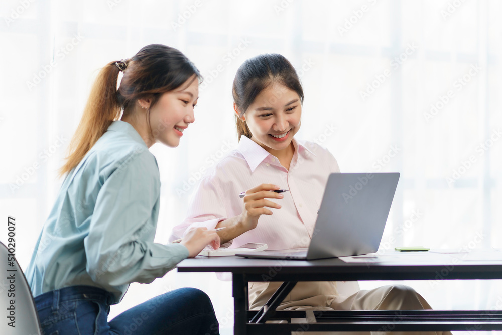 Two young beautiful Asian business woman in the conversation, exchanging ideas on laptop computer together at office. Two young beautiful Asian business woman in the conversation, exchanging ideas on laptop computer together at office.