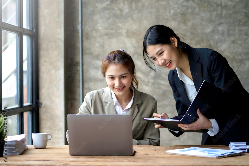 Two young beautiful Asian business woman in the conversation, exchanging ideas on laptop computer together at office. Two young beautiful Asian business woman in the conversation, exchanging ideas on laptop computer together at office.