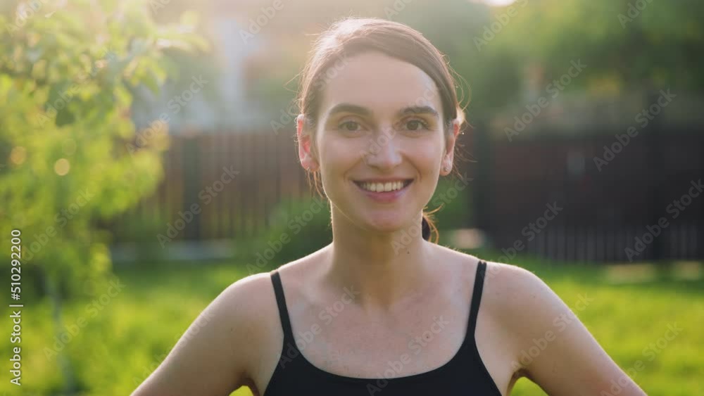 Portrait young attractive smile woman look at camera at the garden. Outdoor portrait happy female sport girl having good time wandering around the threes in sunset. Portrait young attractive smile woman look at camera at the garden. Outdoor portrait happy female sport girl having good time wandering around the threes in sunset.