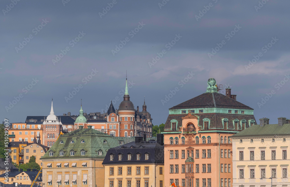 Facades, roofs and towers of 1800s houses in the old town Gamla Stan and the district Södermalm at sunrise a sunny day in Stockholm