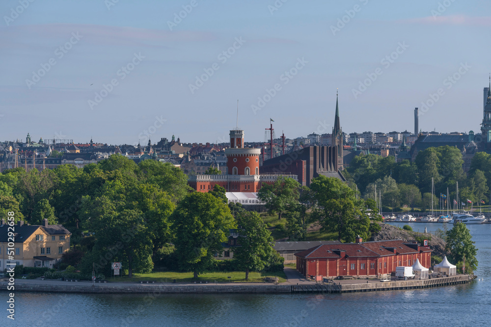 The island Kastellholmen with a castle and an old coal storage building at a pier at sunrise a sunny day in Stockholm