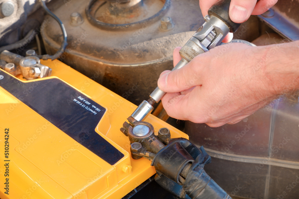 The car mechanic is about to remove the battery to replace the new battery of the car in the car repair shop. The car mechanic is about to remove the battery to replace the new battery of the car in the car repair shop.