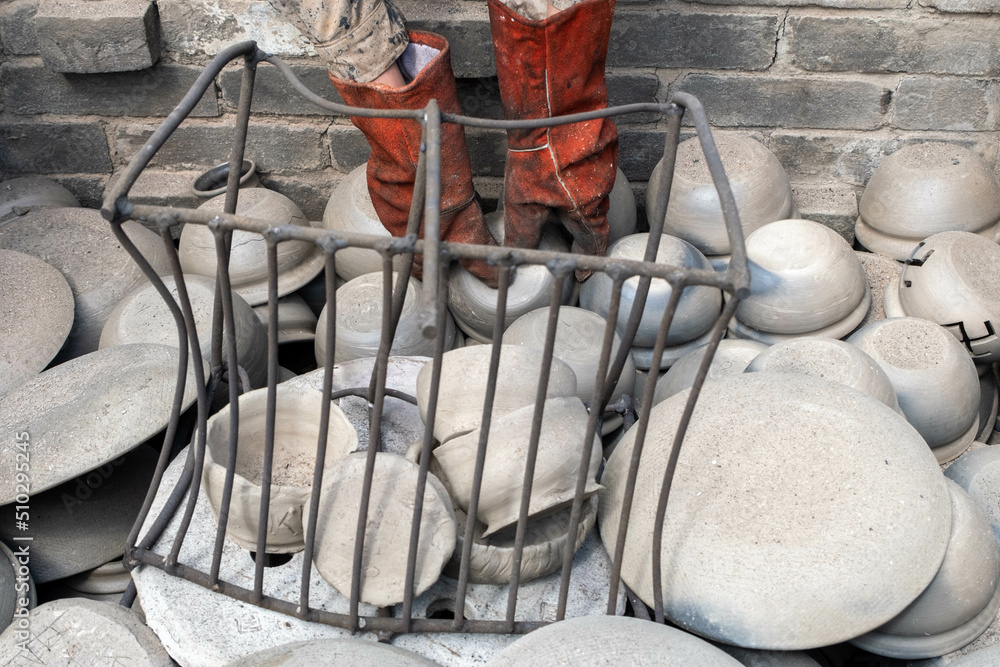 Fototapeta premium opening of a ceramic kiln, Unique handmade pots and dishes of clay getting black after firing and oxygen reducing process in wood fire kiln. Latvian national crafts.