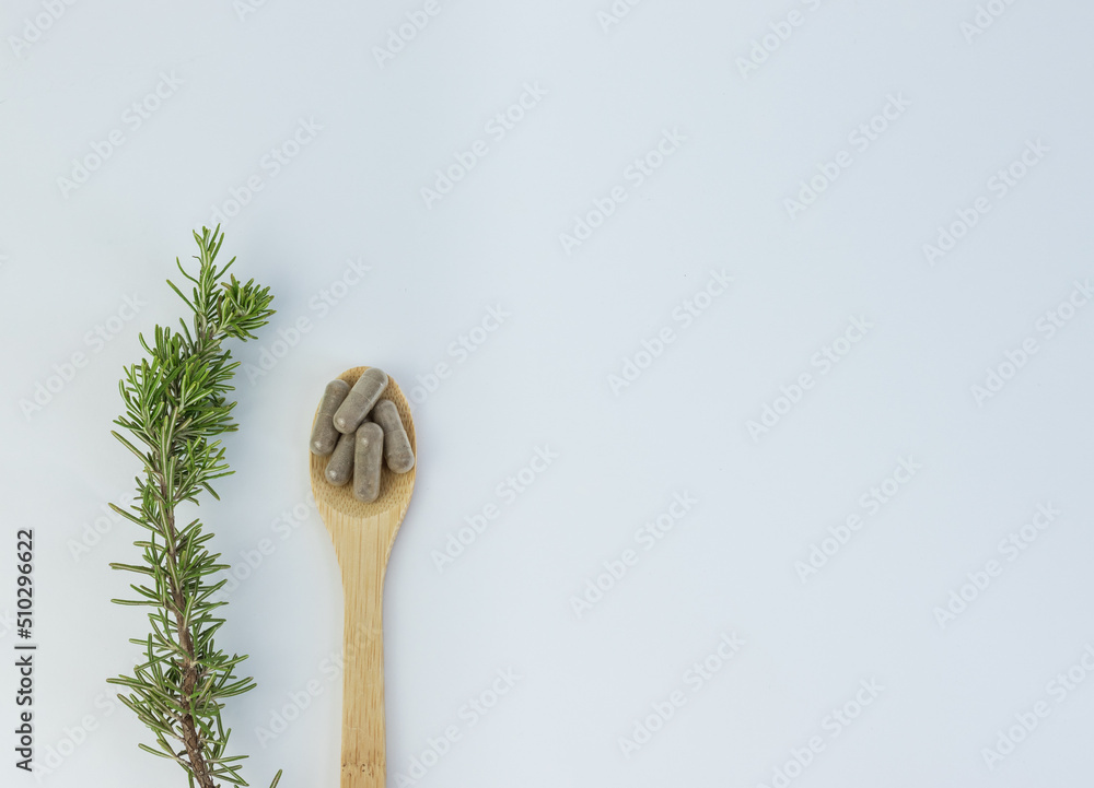 Wooden spoon with vitamins and rosemary branch on white background Wooden spoon with vitamins and rosemary branch on white background