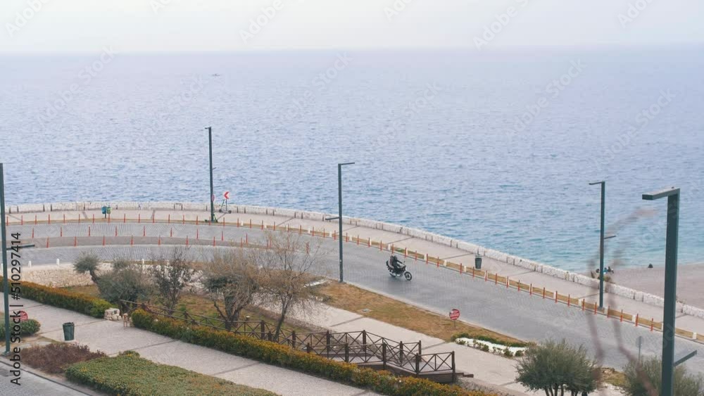People riding bikes and cars on the road by the sea