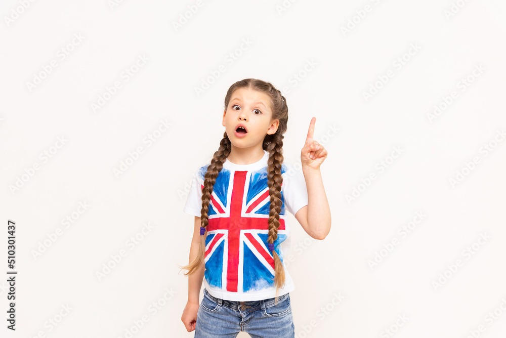 A little girl in a T-shirt with the flag of Great Britain points up at your advertisement on an isolated white background. A little girl in a T-shirt with the flag of Great Britain points up at your advertisement on an isolated white background.