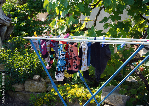Metal clothes dryer. He stands outside drying colored socks.