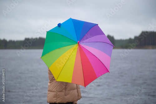 A woman with a multicolored umbrella on the street during the rain.