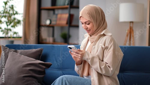 Smiling Muslim modern woman chatting texting message browsing internet smartphone  photo