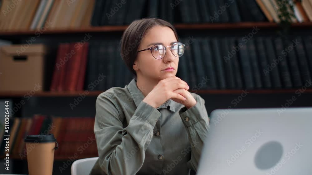 Pensive academic female working laptop at library desk thinking planning job educational project Pensive academic female working laptop at library desk thinking planning job educational project