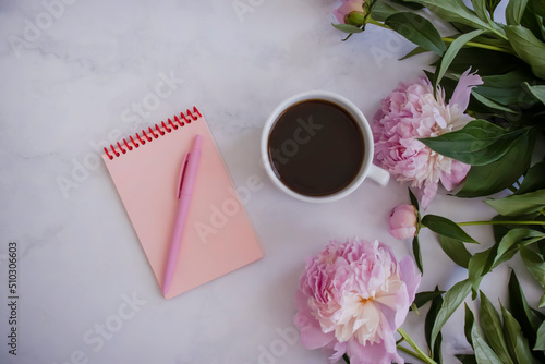 Cup of coffee, peony flower, notebook on a light background