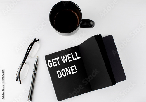GET WELL DONE written text in small black notebook with coffee , pen and glasess on white background. Black-white style