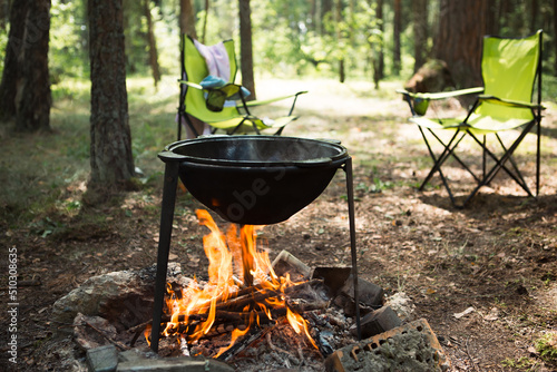 Cooking at a campsite on an open fire in a cauldron. Outdoor picnic, summer vacation, travel accessories